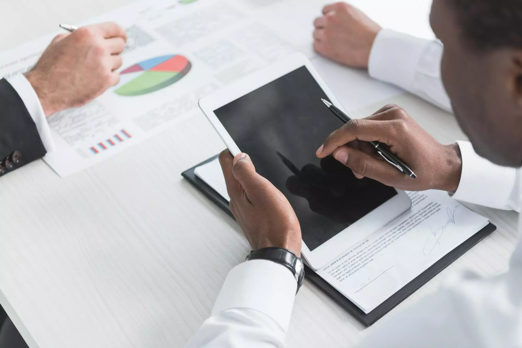 cropped-shot-of-african-american-businessman-using-tablet-during-business-meeting-with-colleagues.jpg